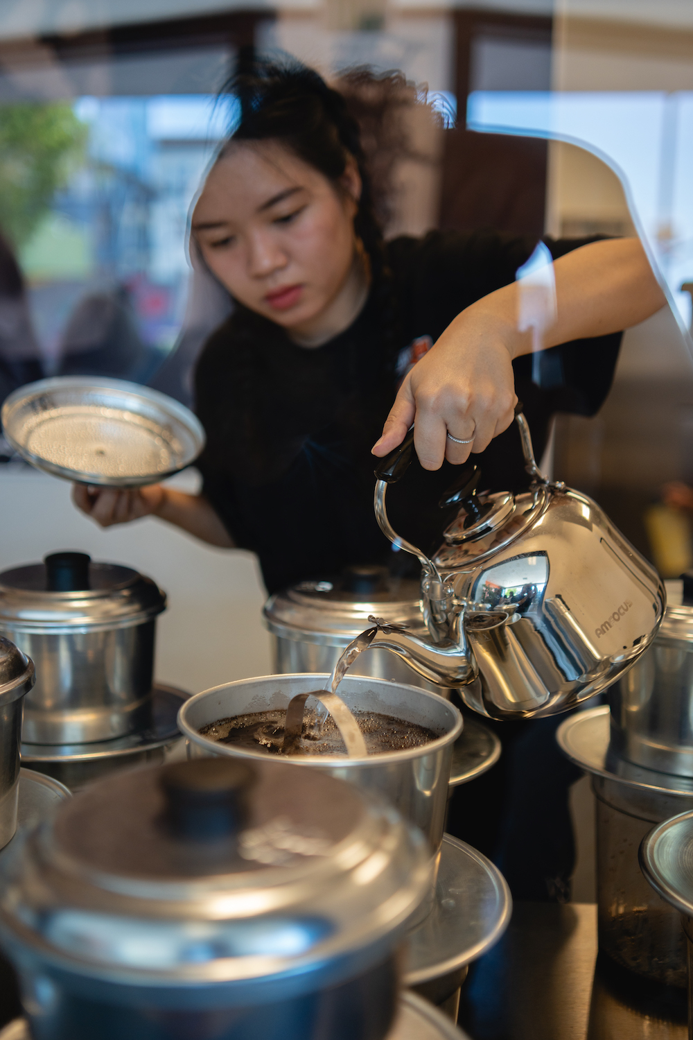 A woman pouring coffee at San Diego coffeeshop Saigon Coffee in North Park