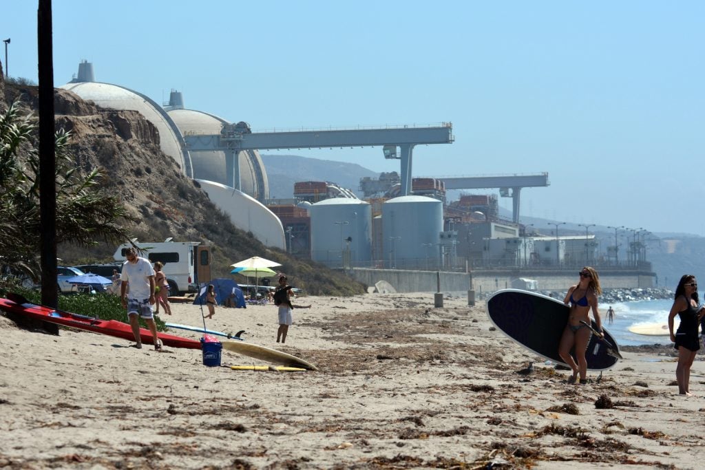 San Onofre Nuclear Generating Station and power plant near San Diego and Los Angeles with people surfing on the beach nearby