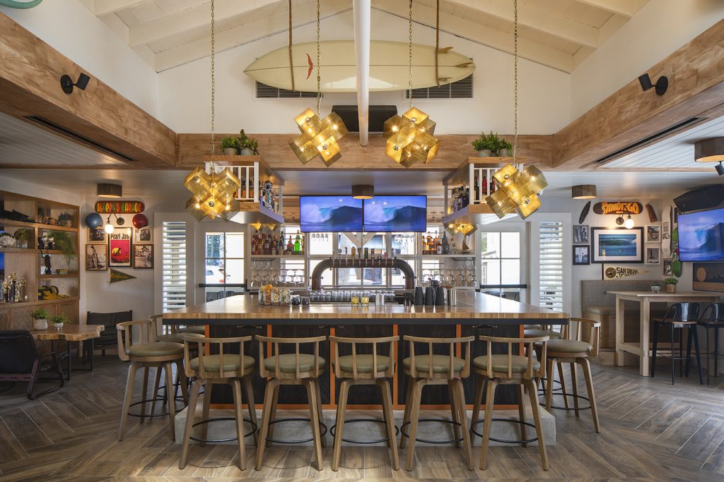 Interior of new San Diego restaurant and bar Hideaway Pacific Beach featuring a surfboard and various beach decorations