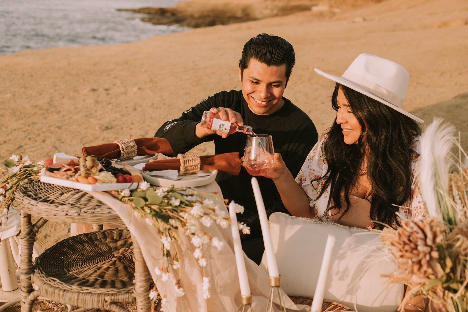 A couple sharing a glass of wine while on a date picnicking at Sunset Cliffs, San Diego