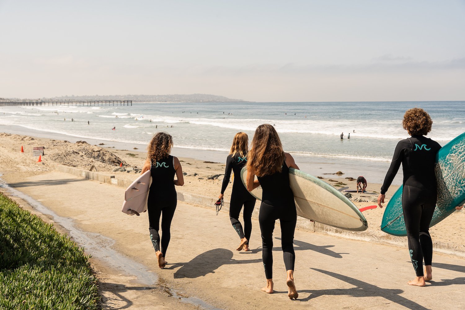 Free activities and things to do in San Diego featuring surfers walking on the beach at Tourmaline, Pacific Beach