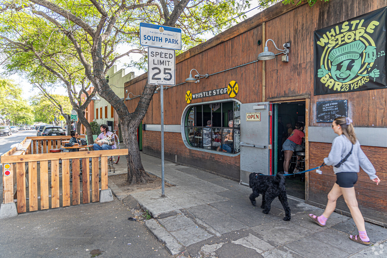 Things to do in South Park, San Diego featuring a woman walking her dog past South Park bar Whistlestop