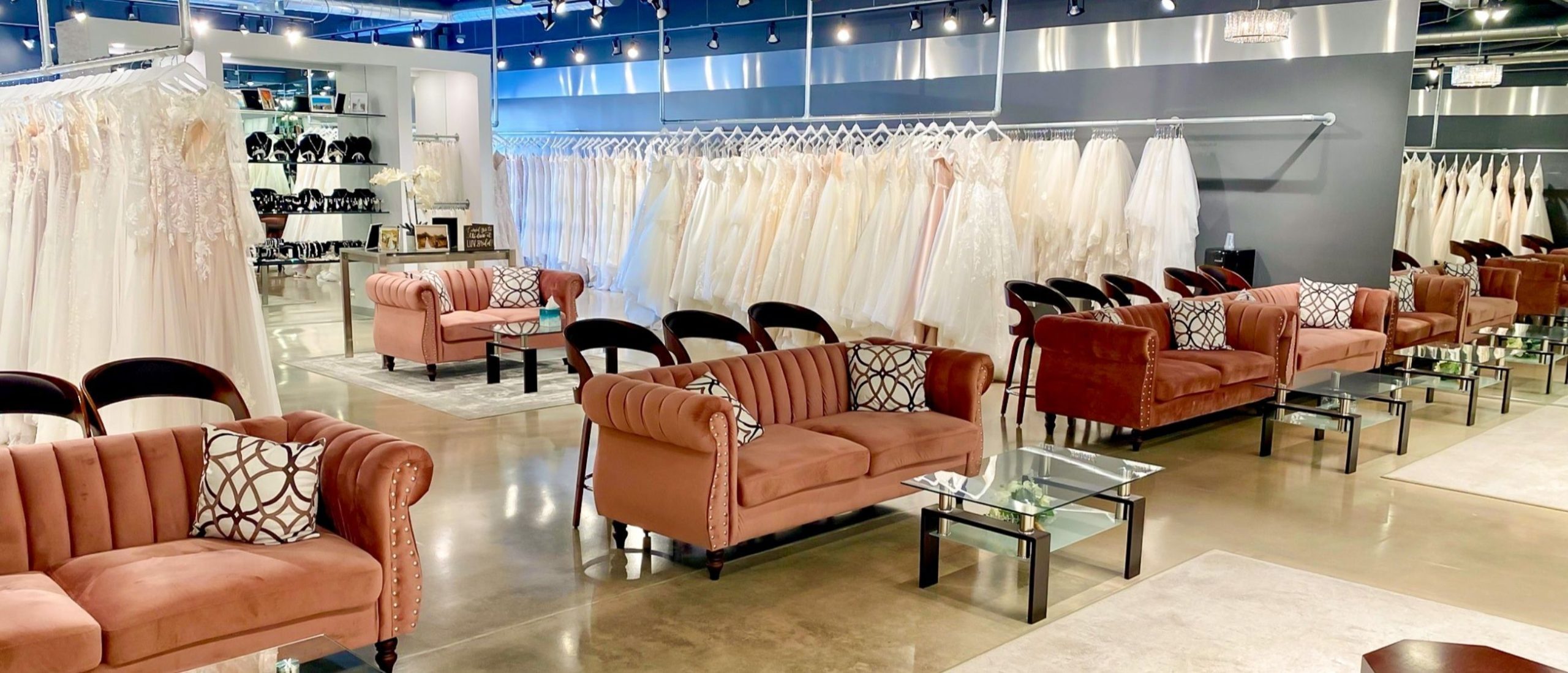 Interior view of LUV Bridal bridal shop and salon in Linda Vista, San Diego, with clothing racks and couches