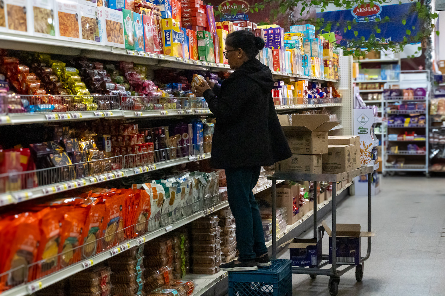 Interior of Miramar's Akshar Cash & Carry featuring an employee stocking food in an aisle