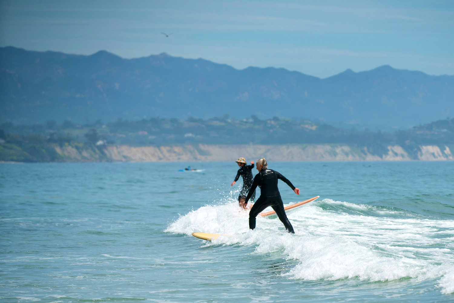 Arkin and Kirker of the Wahine Kai women's surf club riding waves at Campus Point