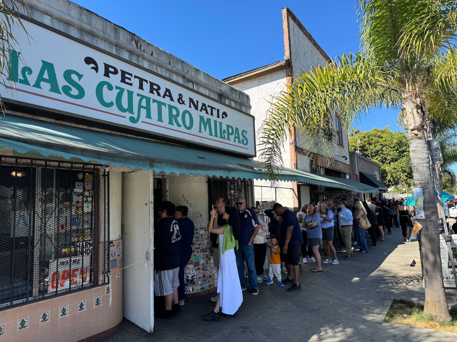 San Diego Mexican restaurant Las Cuatro Milpas exterior in Barrio Logan featuring line of customers who believed rumors that the shop was closing