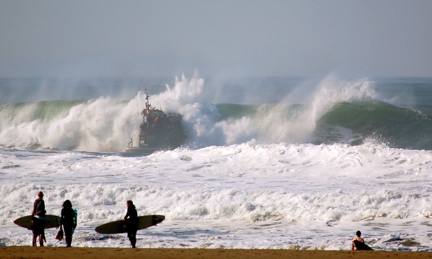 Best California surf spots featuring Ocean Beach San Francisco surfers with a coast guard boat in the background