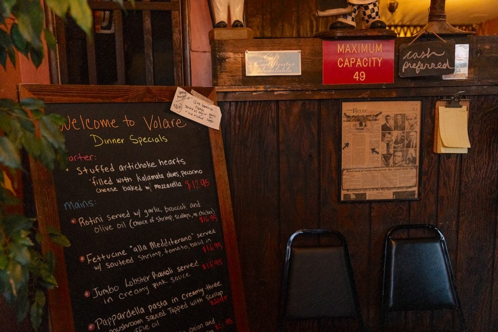 Interior of Volare Italian Restaurant in Point Loma, San Diego featuring a specials menu and a cash only sign