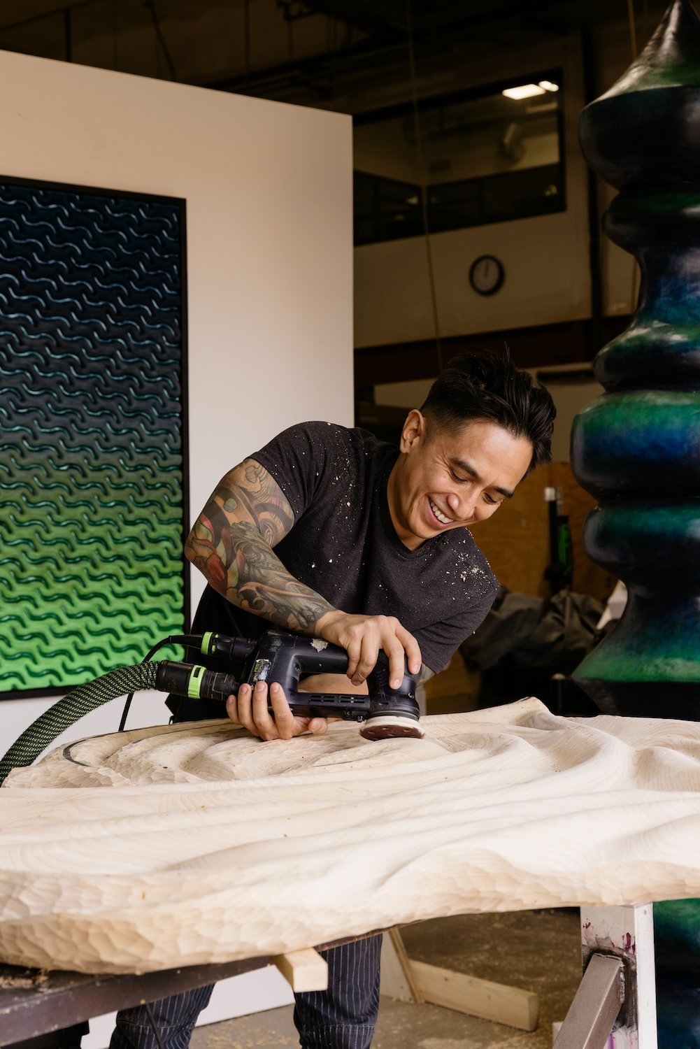 San Diego artists and wood sculptor Dan "Nuge" Nguyen working on a wavy wooden sculpture in the Maketory in Miramar 