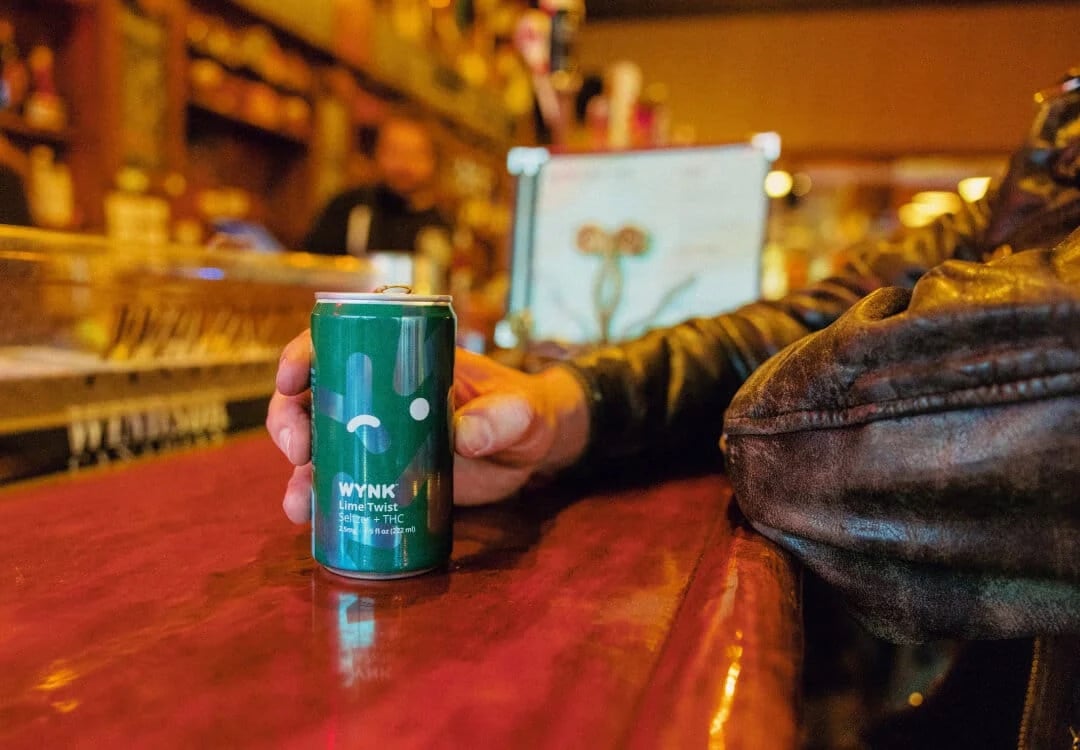 THC-infused cannabis drink WYNK featuring a person at a bar