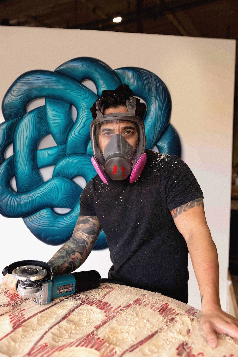 San Diego artists and wood sculptor Dan "Nuge" Nguyen in his workshop at Miramar's Maketory with "Viper Pit" behind him