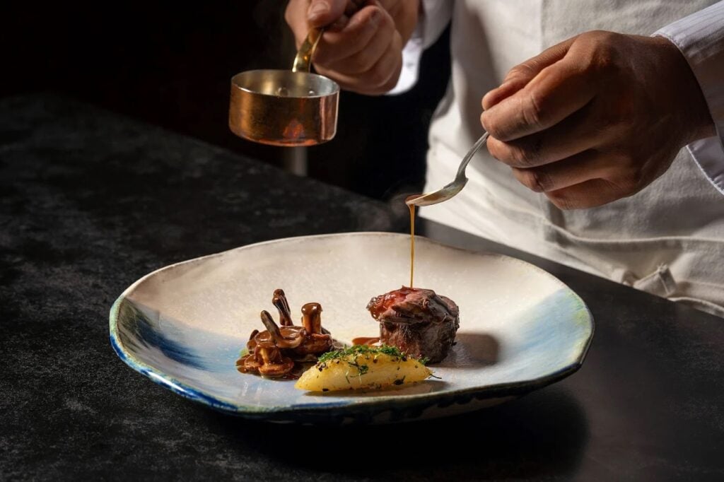A chef preparing food at new La Jolla restaurant Lucien featuring Michelin-starred chefs and founded by Elijah Arizmendi