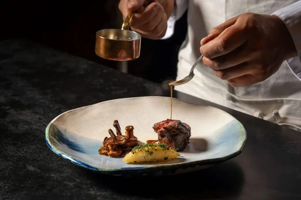 A chef preparing food at new La Jolla restaurant Lucien featuring Michelin-starred chefs and founded by Elijah Arizmendi
