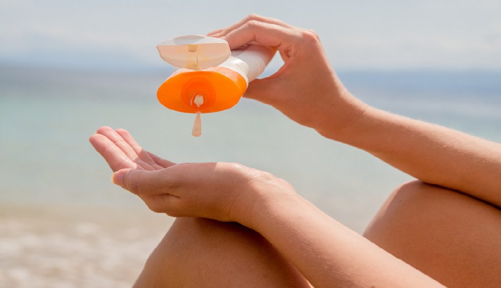 The best skincare routine for sun protection according to  dermatologists featuring someone putting on sunscreen