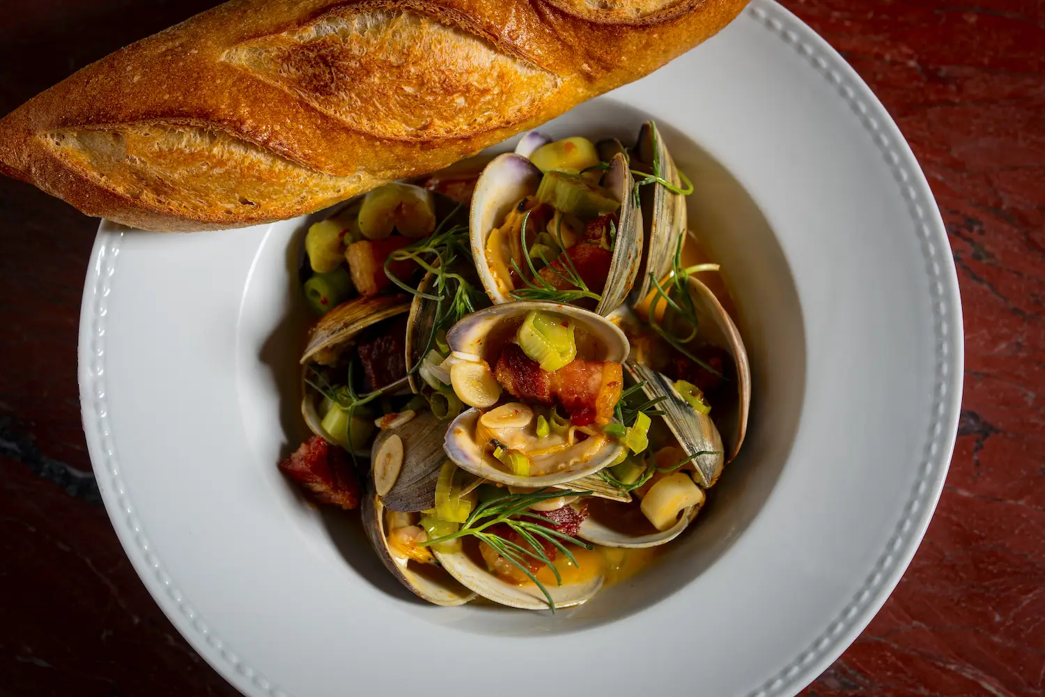 Food from San Diego restaurant Le Coq in La Jolla with new menu additions including Clams and pork belly with Tokyo negi