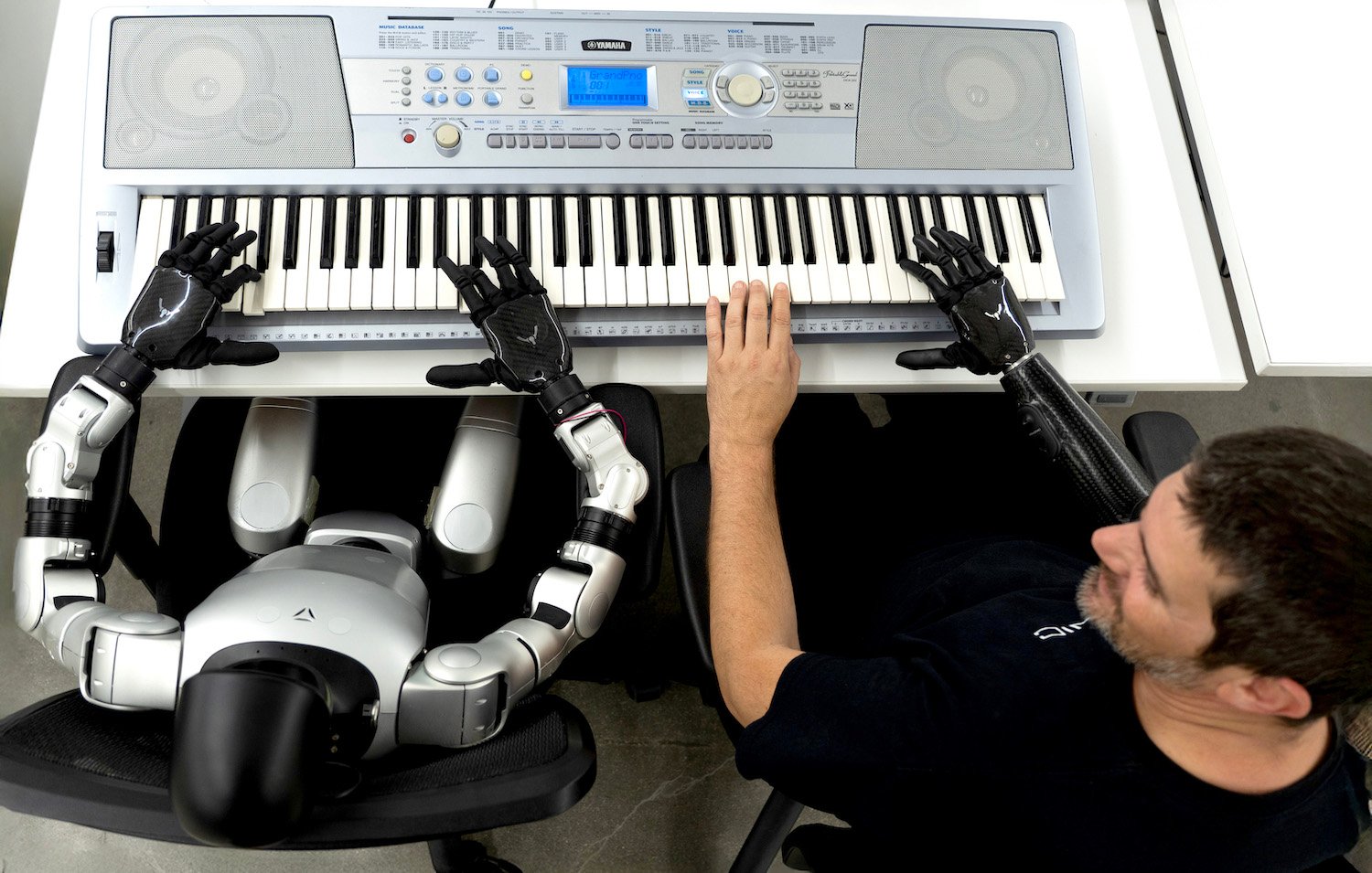 Man with Psyonic's ability hand bionic planing the piano with a robot 